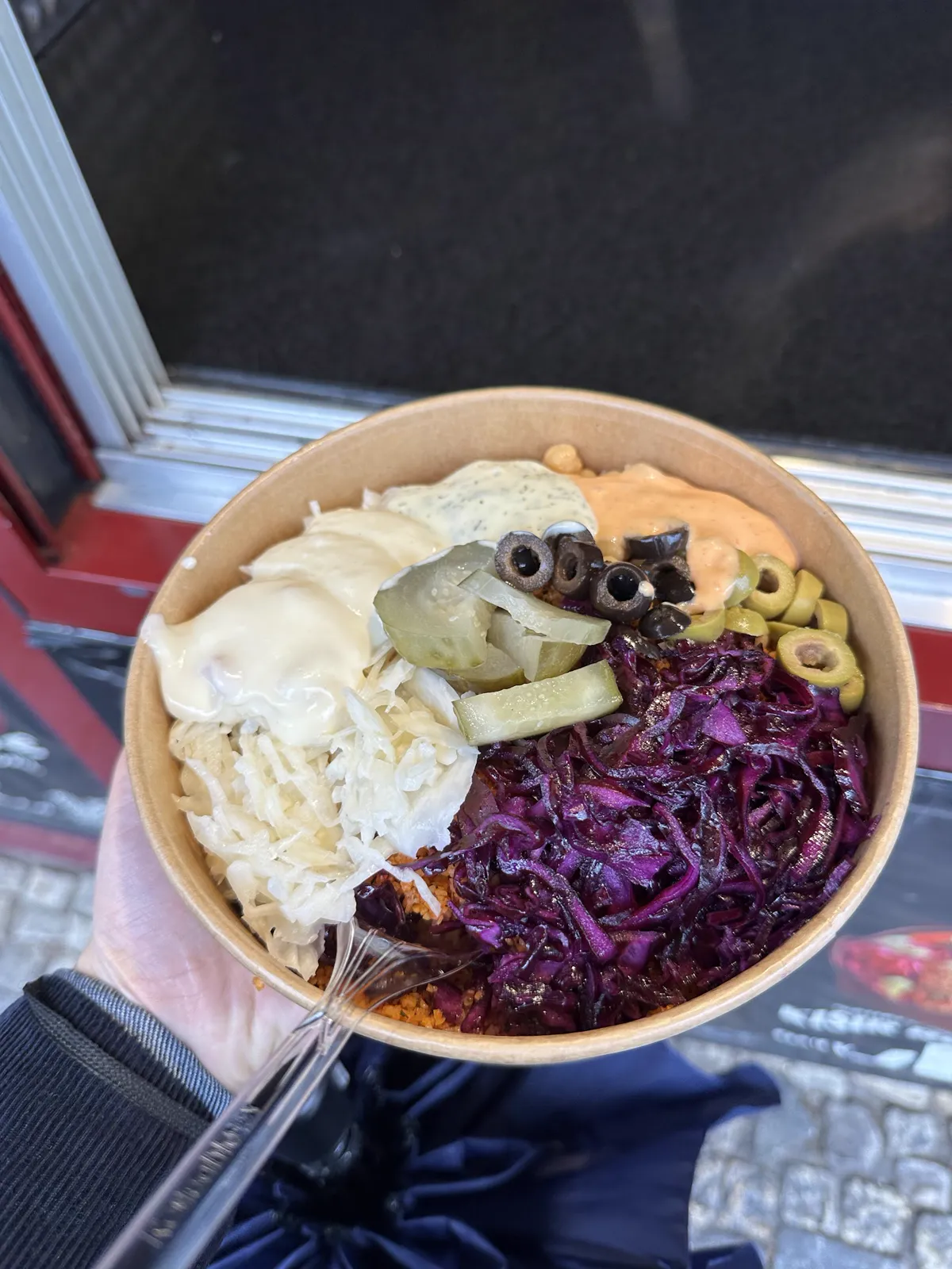 Kisir-Bowl von oben im Kraft-Karton: Rotkohl, Krautsalat, Gurken, Oliven und Saucen